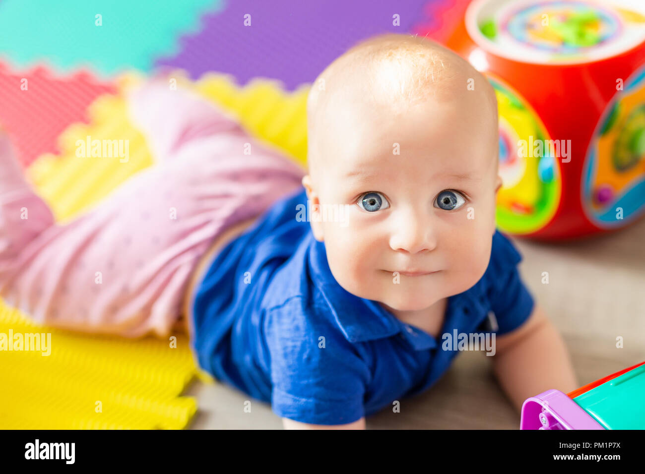 Portrait Of Cute Baby Boy Lying On Floor Covered With Multicolored