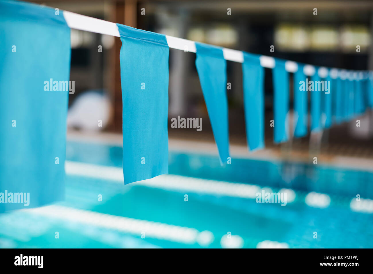 Row of blue flags hanging on white ribbon over swimmingpool as border