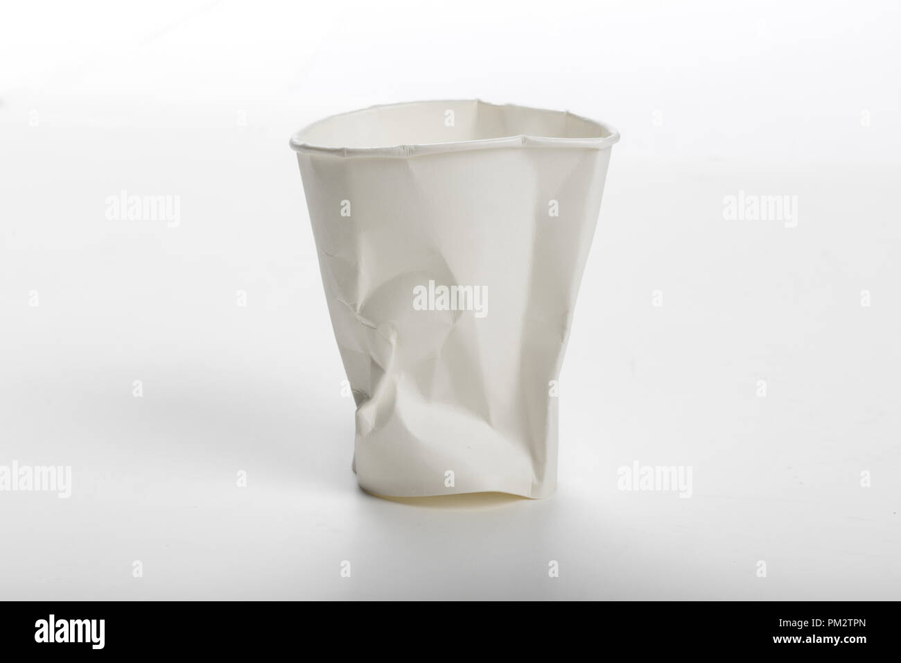 Crumbled White paper coffee cup on white background. Stock Photo