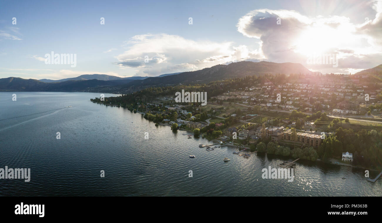 Aerial panoramic view of a small town on the hill near Okanagan Lake during a vibrant summer sunset. Taken in Peachland, BC, Canada. Stock Photo