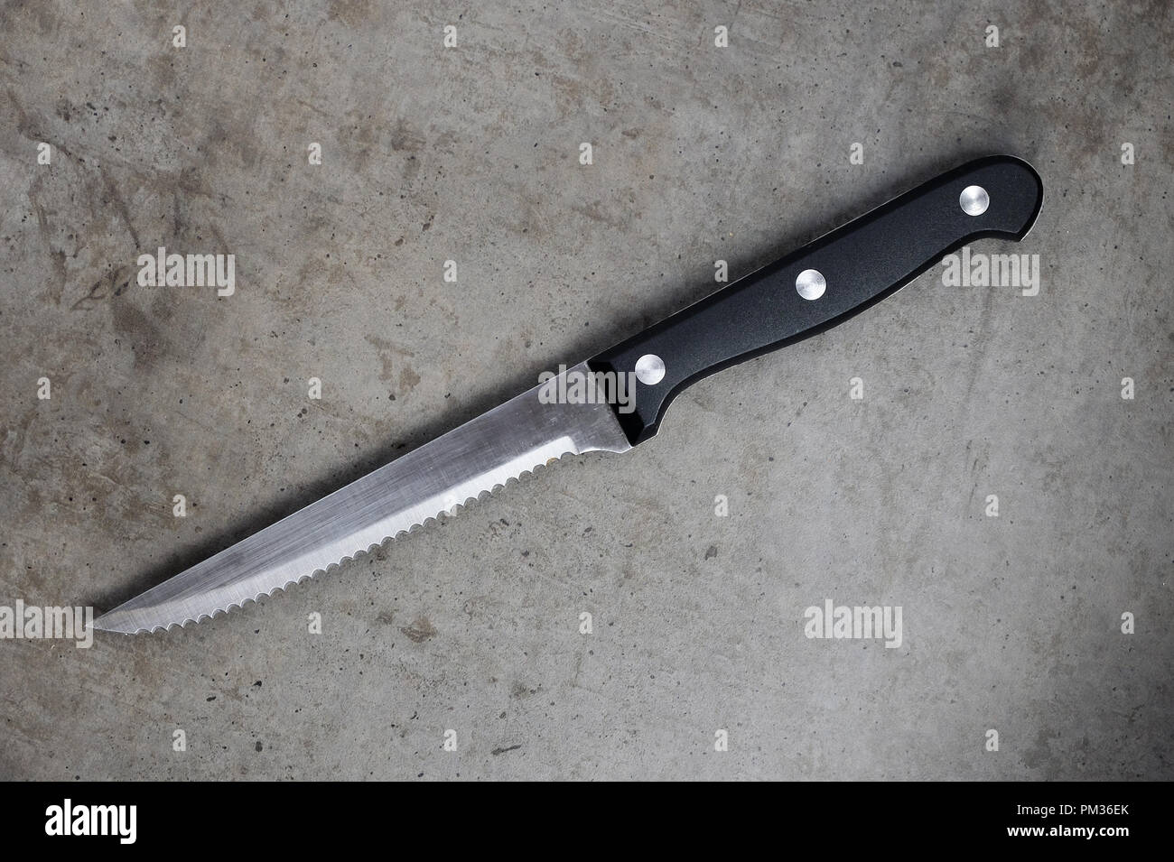 https://c8.alamy.com/comp/PM36EK/serrated-knife-on-a-dark-gray-concrete-table-PM36EK.jpg