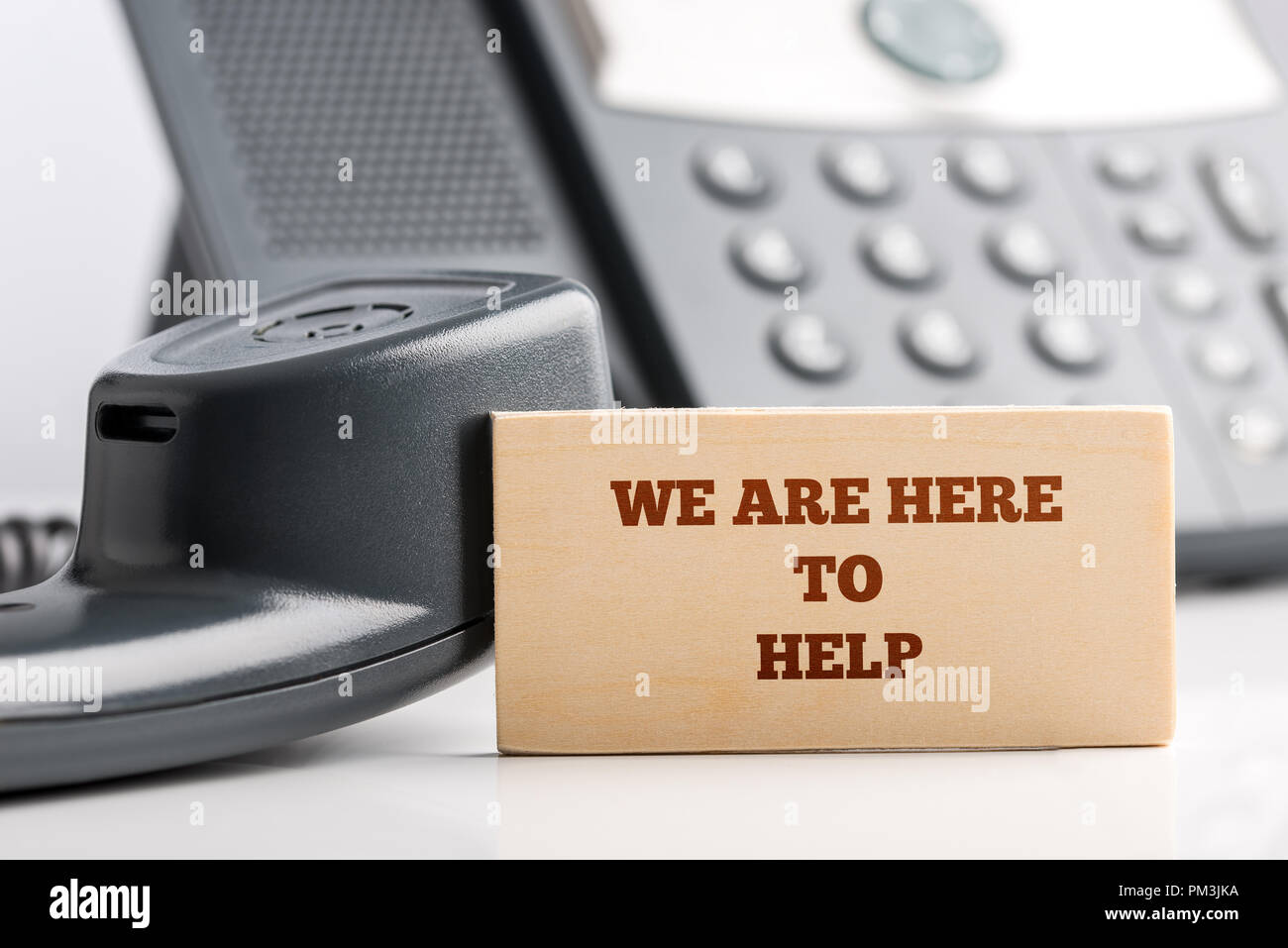 Simple Customer Support Concept Design- Close up of Small Wooden Piece with We are Here to Help Texts at the Customer Service Operator Desk with Telep Stock Photo