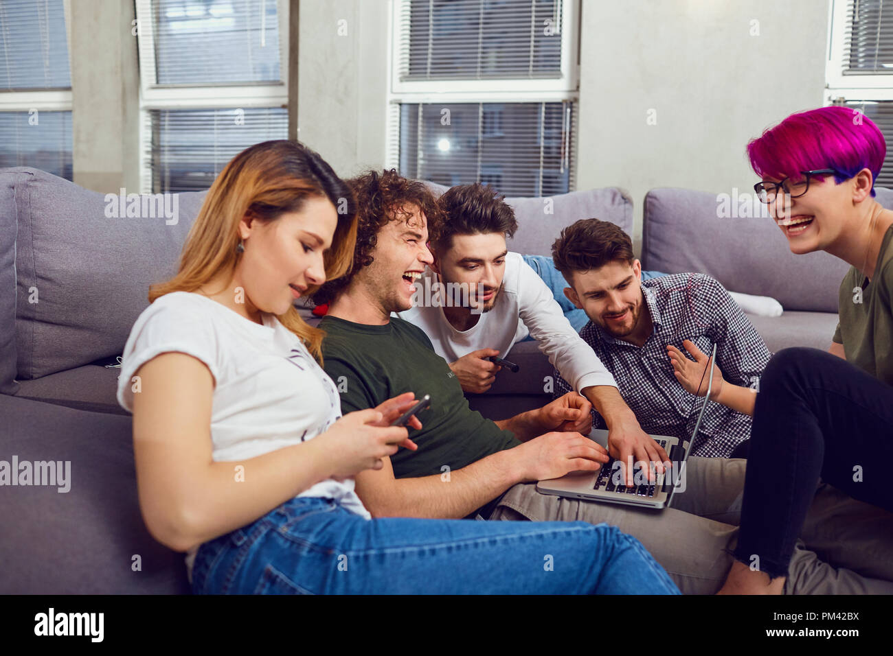 A group of friends of students in leisure with a laptop in a roo Stock Photo