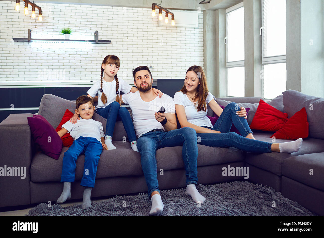 A family with a remote control looks at TV in the room. Stock Photo