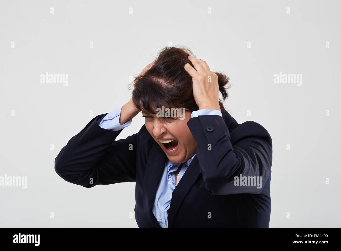 Mature businesswoman having a nervous breakdown, isolated on gray ...