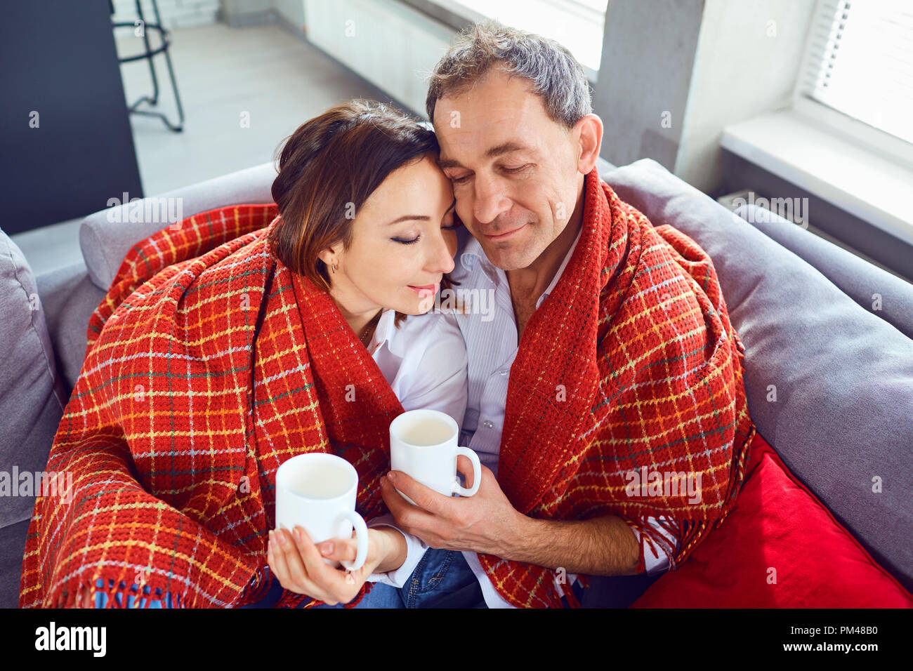 A happy couple in middle age under a rug rests comfortably toget Stock Photo