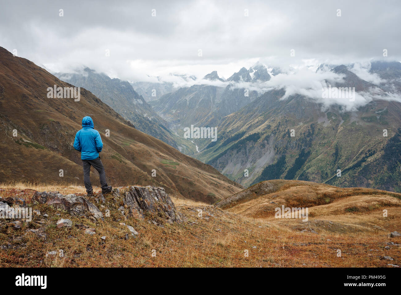 Tourist enjoys the view of the mountains. Guy on a trekking in the Caucasus Mountains. Location near Koruldi Lakes. Samegrelo-zemo svaneti, Georgia Stock Photo