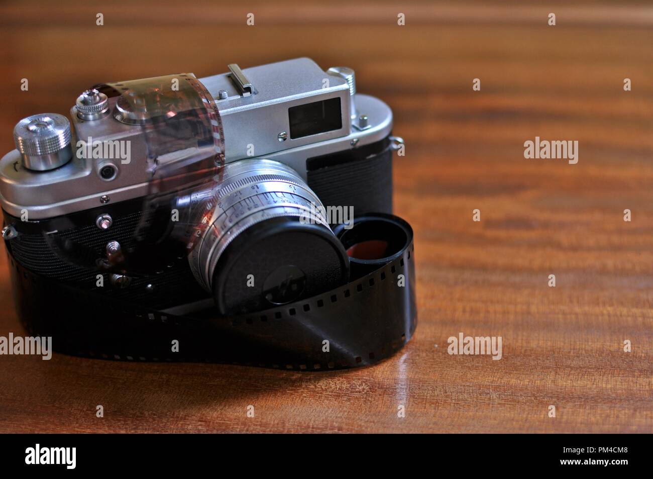 Old photo camera with retro style reel (roll) film 35 mm wrapped, on wooden  background. Front side view Stock Photo - Alamy