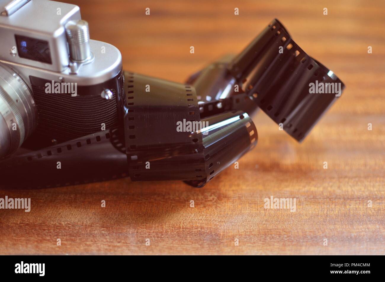 A part of an old photo camera with retro style reel (roll) film 35 mm wrapped, on wooden background. Front top side view Stock Photo