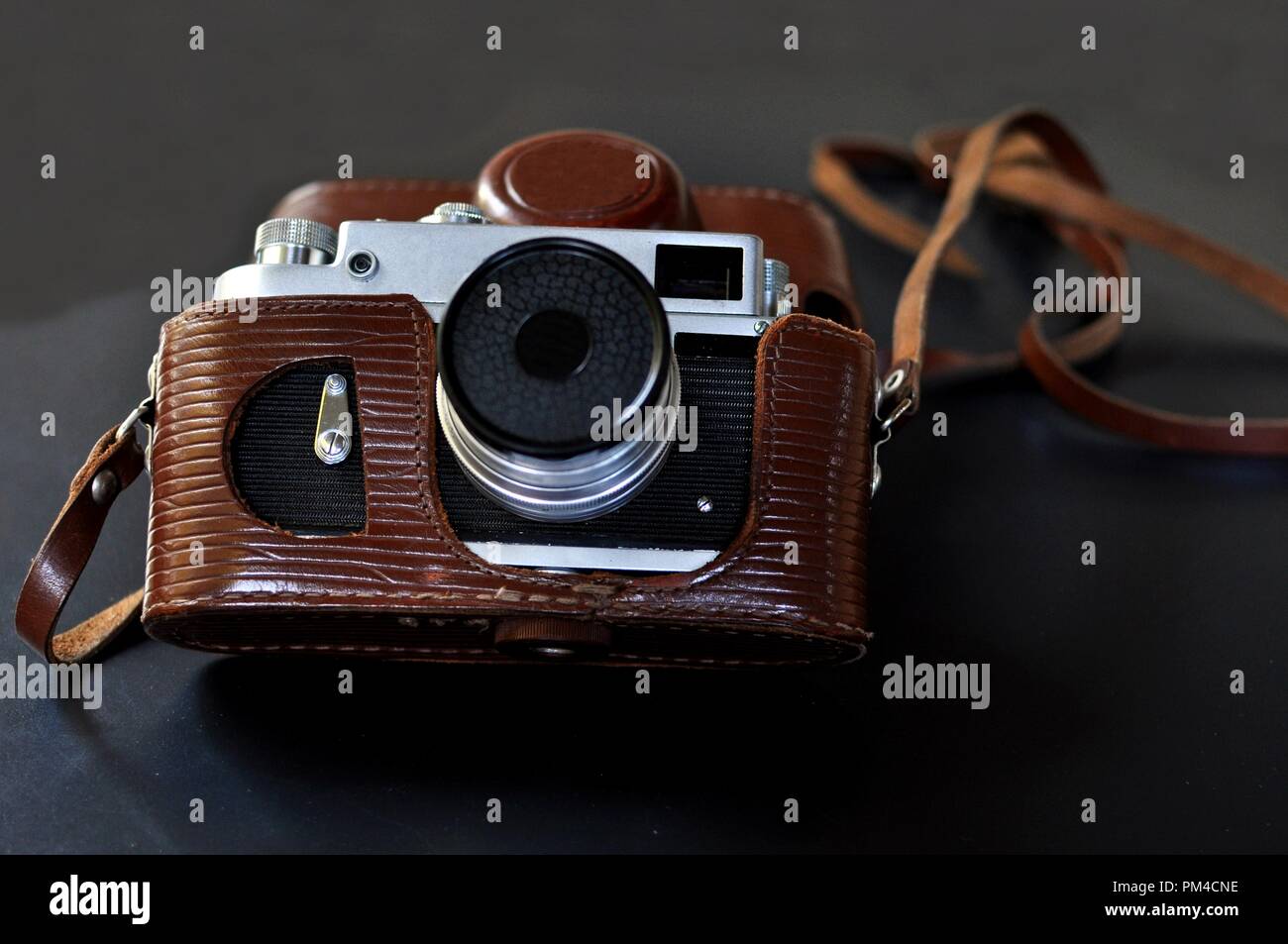 Vintage old film camera with brown leather case, on black background Stock Photo