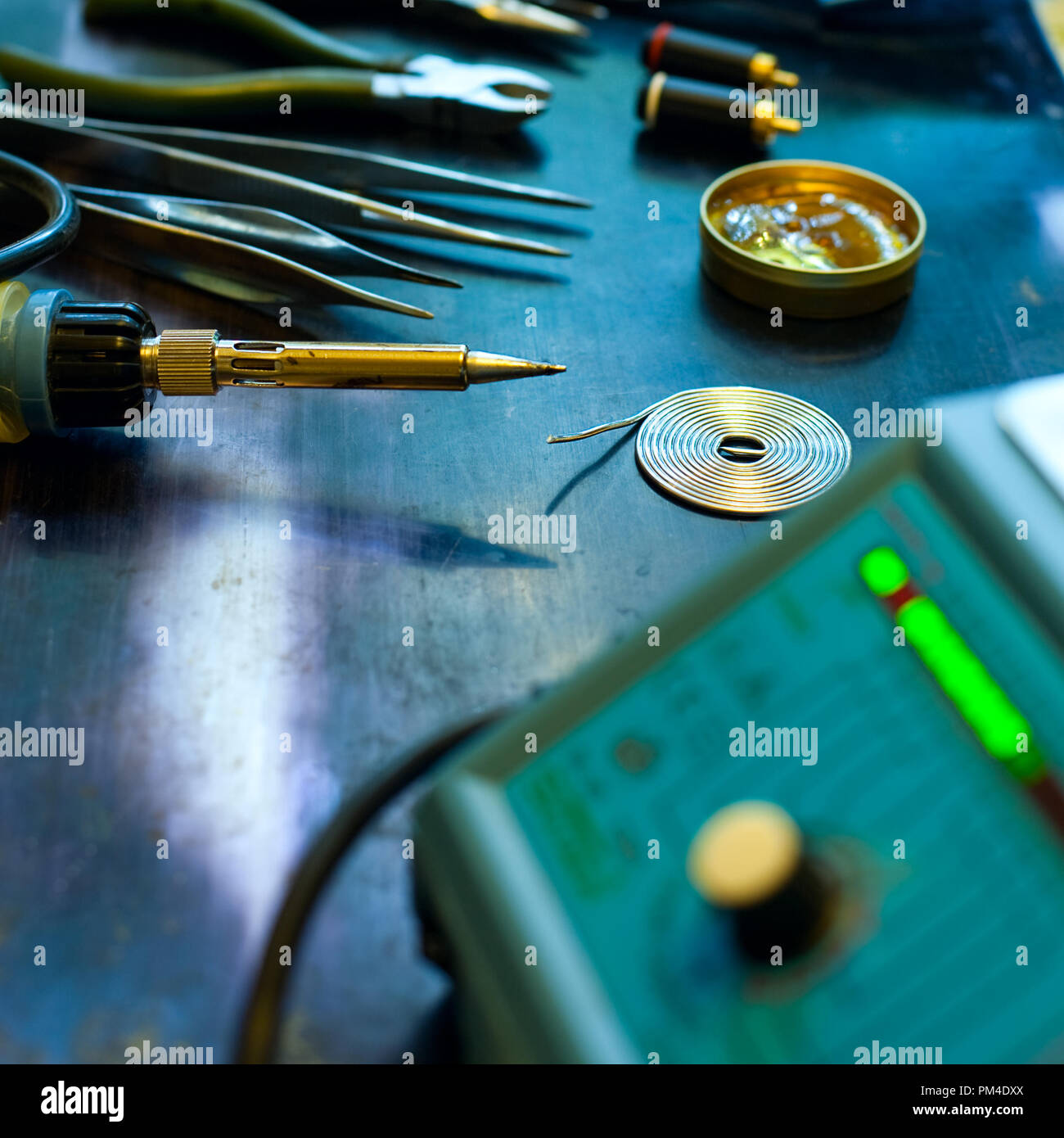 Soldering station with soft solder and tools in background, shallow DOF