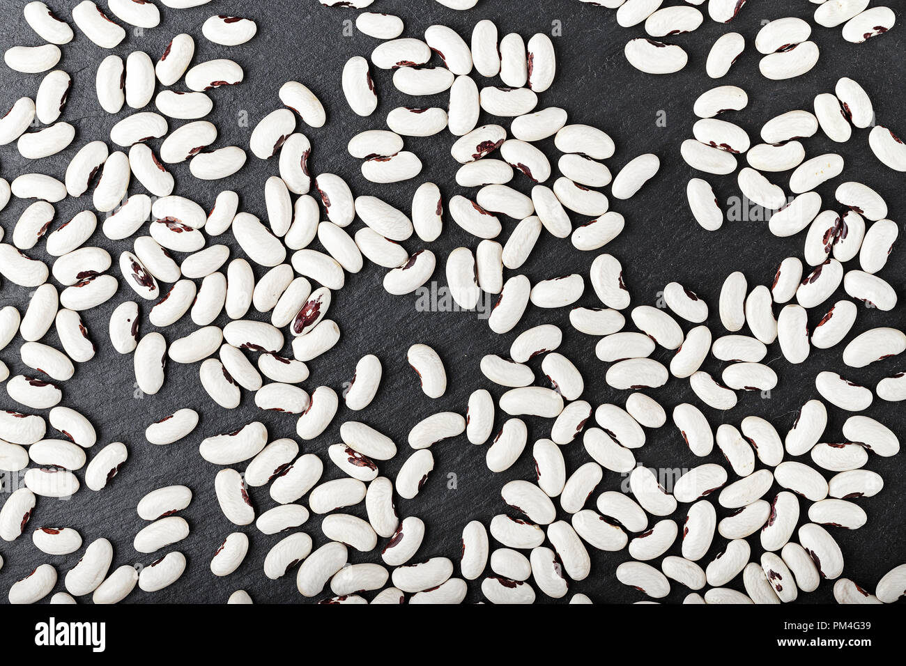 healthy nutritious food uncooked kidney beans scattered on a black