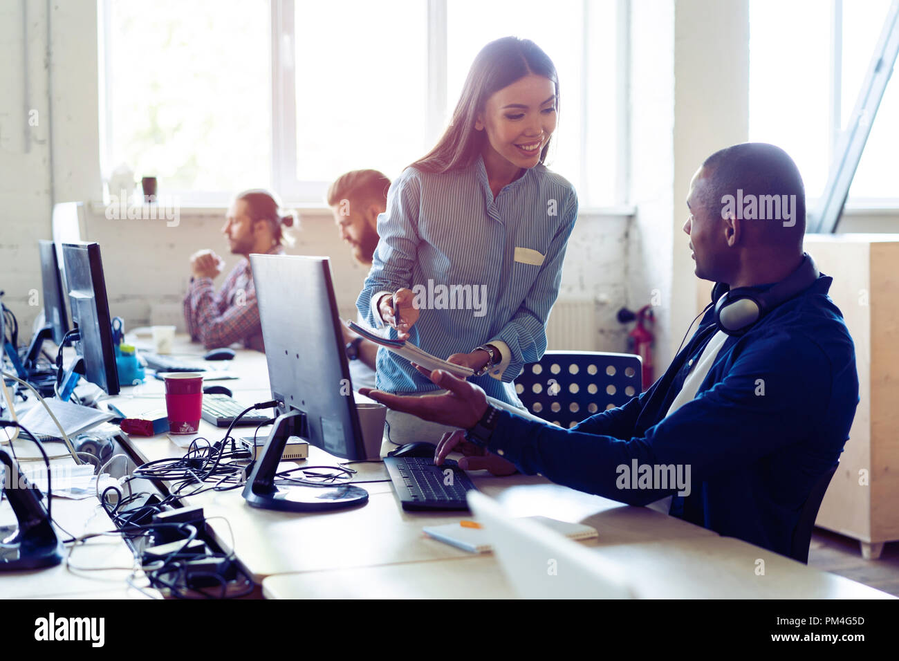 Busy working day. Top view of young modern people in smart casual wear discussing business while sitting in the creative office. Stock Photo