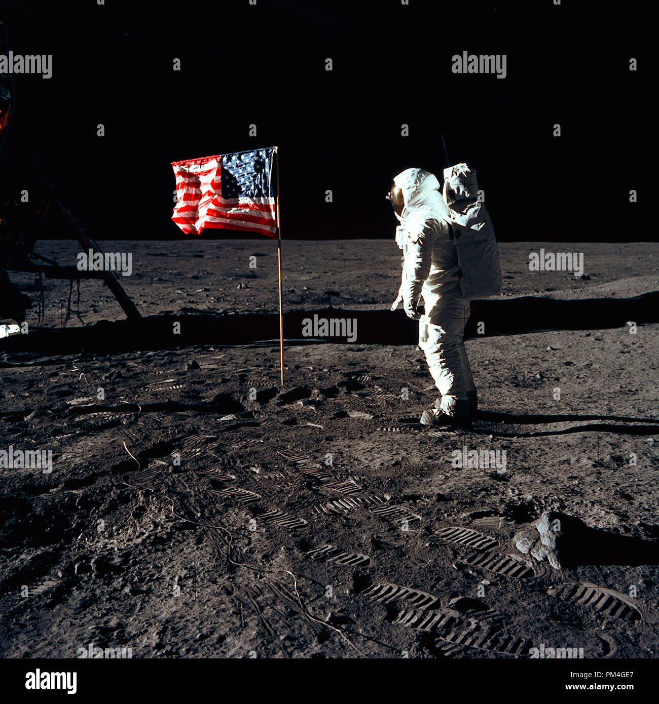 Astronaut Buzz Aldrin, lunar module pilot of the first lunar landing mission, poses for a photograph beside the deployed United States flag during an Apollo 11 Extravehicular Activity (EVA) on the lunar surface. The Lunar Module (LM) is on the left, and the footprints of the astronauts are clearly visible in the soil of the Moon. Astronaut Neil A. Armstrong, commander, took this picture with a 70mm Hasselblad lunar surface camera, July 20, 1969.  File Reference # 1001 012THA Stock Photo