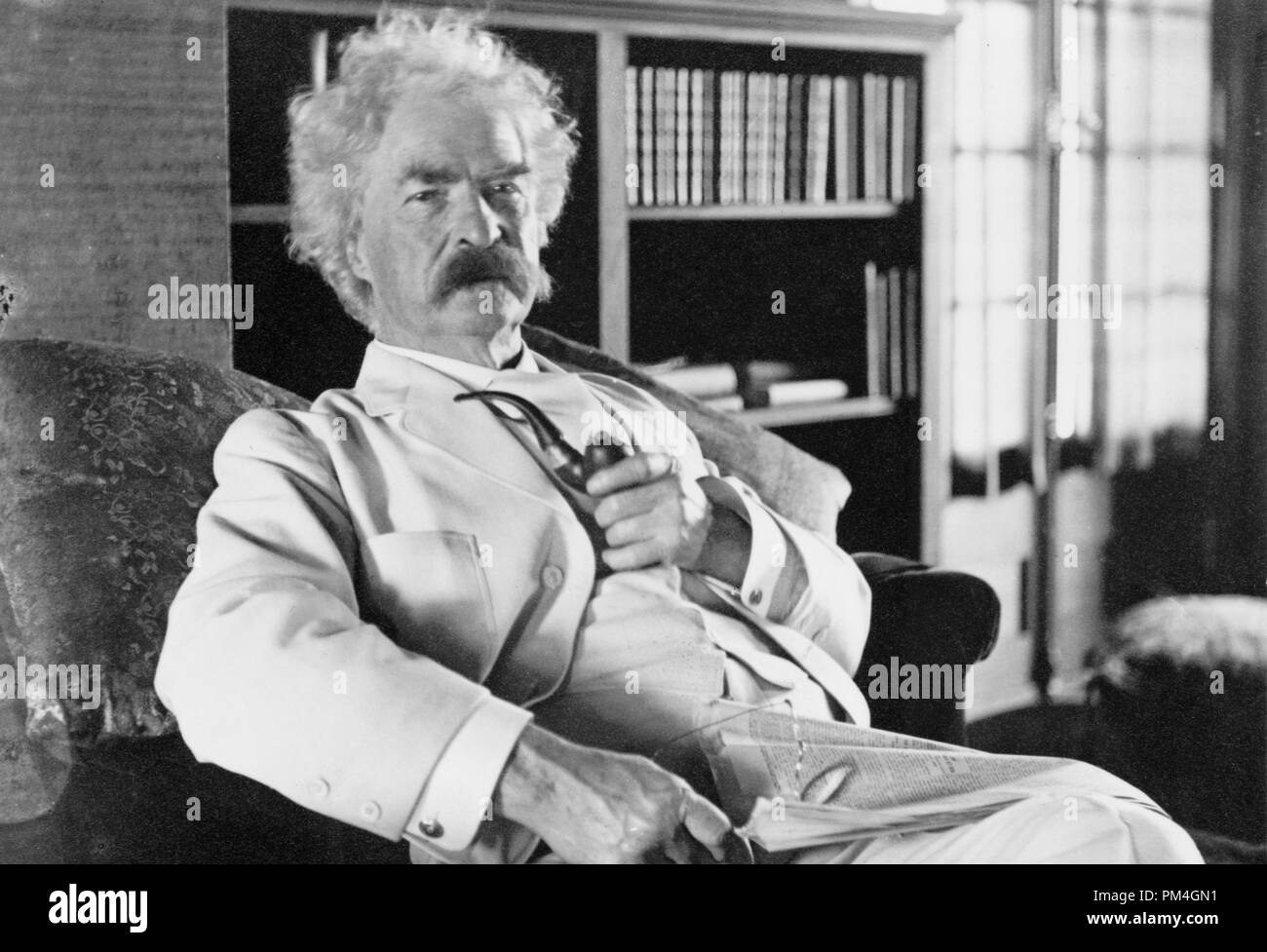 Mark Twain (Samuel L. Clemens), three-quarter length portrait, seated, facing slightly right, holding pipe, circa 1905.  File Reference # 1003_066THA Stock Photo