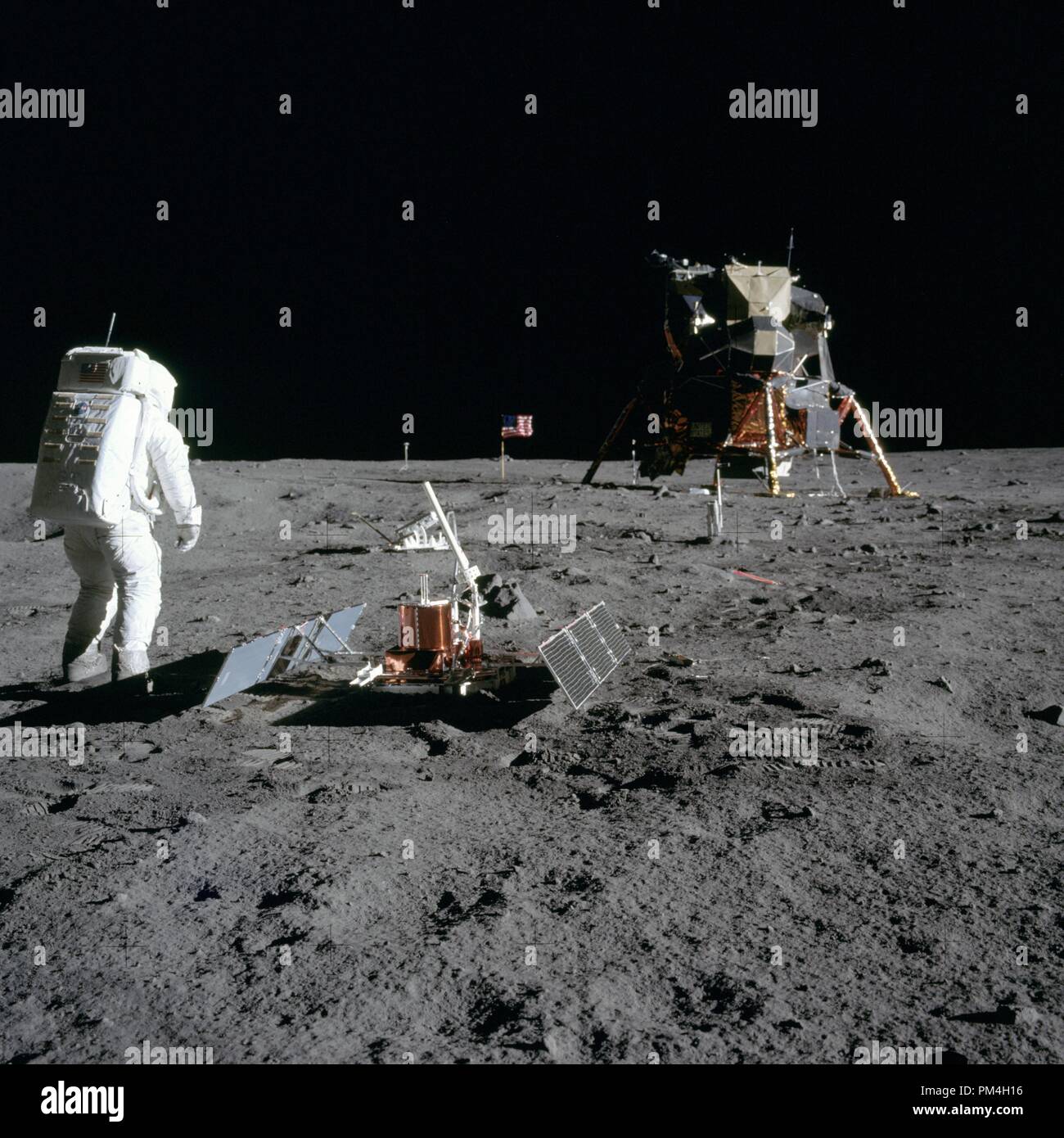 (20 July 1969) --- Astronaut Edwin E. Aldrin Jr., lunar module pilot, is photographed during the Apollo 11 extravehicular activity (EVA) on the moon. He has just deployed the Early Apollo Scientific Experiments Package (EASEP). This is a good view of the deployed equipment. In the foreground is the Passive Seismic Experiment Package (PSEP); beyond it is the Laser Ranging Retro-Reflector (LR-3); in the center background is the United States flag; in the left background is the black and white lunar surface television camera; in the far right background is the Lunar Module (LM). Astronaut Neil A. Stock Photo