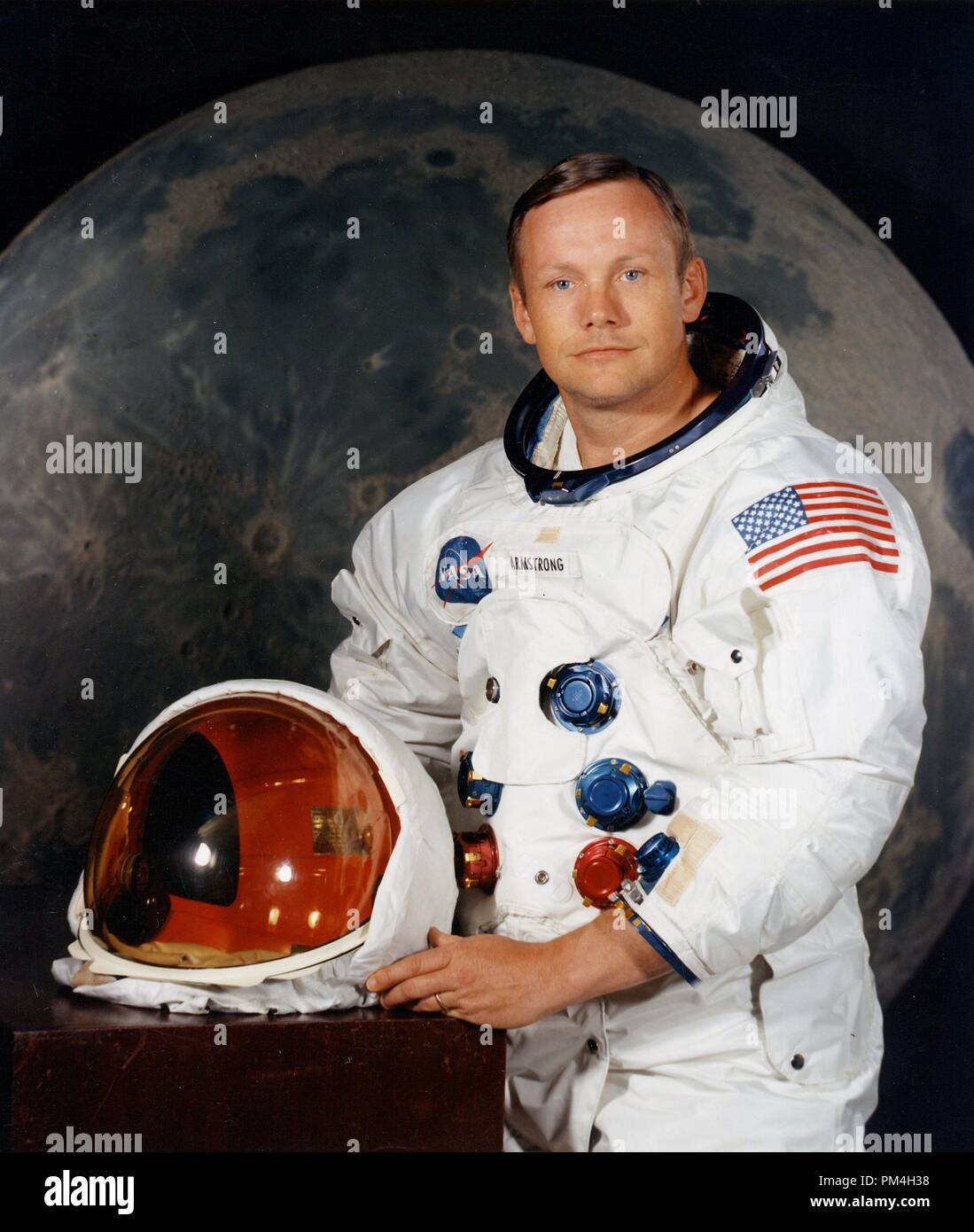 Portrait of Astronaut Neil A. Armstrong, commander of the Apollo 11 Lunar Landing mission in his space suit, with his helmet on the table in front of him. Behind him is a large photograph of the lunar surface.July 1, 1969  File Reference # 1003 201THA Stock Photo