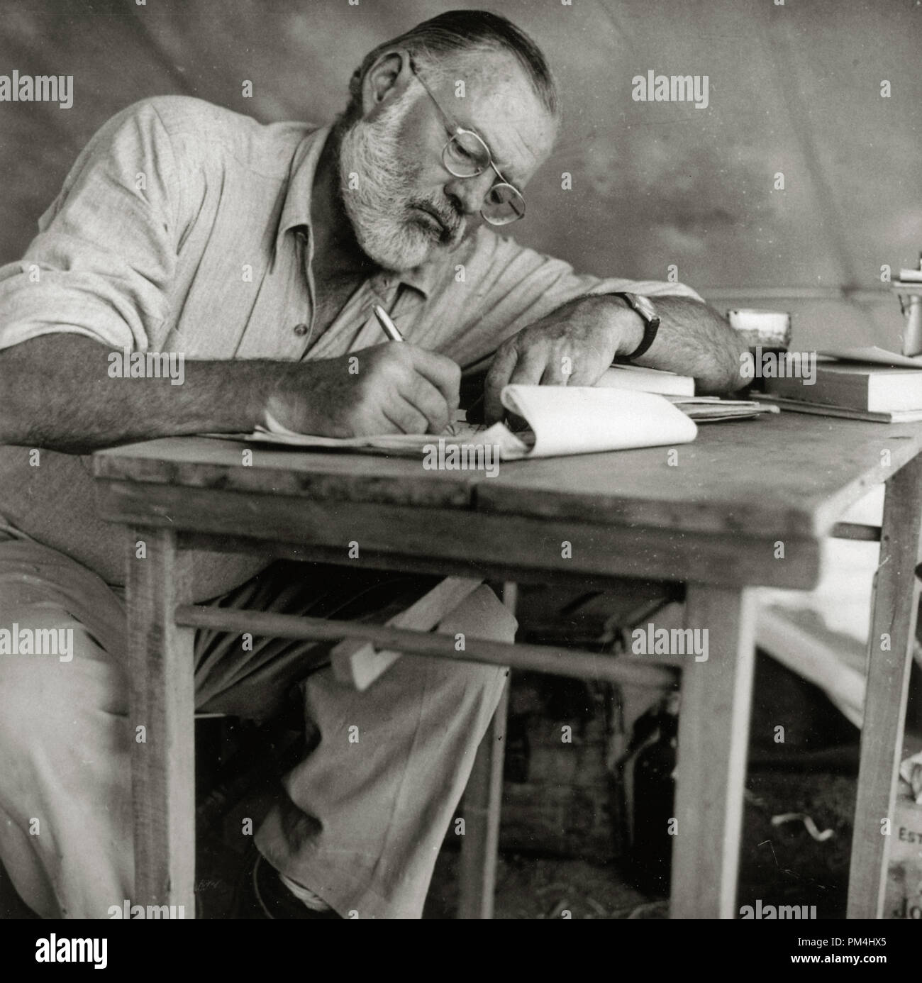 Ernest Hemingway Writing at Campsite in Kenya, circa 1953  File Reference # 1003 427THA Stock Photo