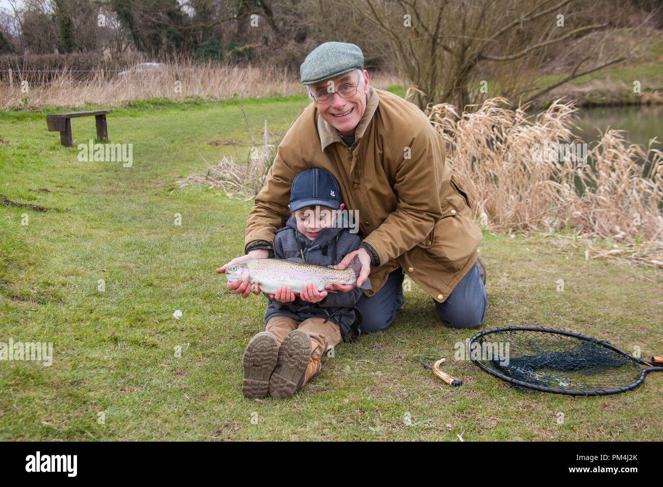Three year old boy and his grandfather fly fishing at Moorhen trout