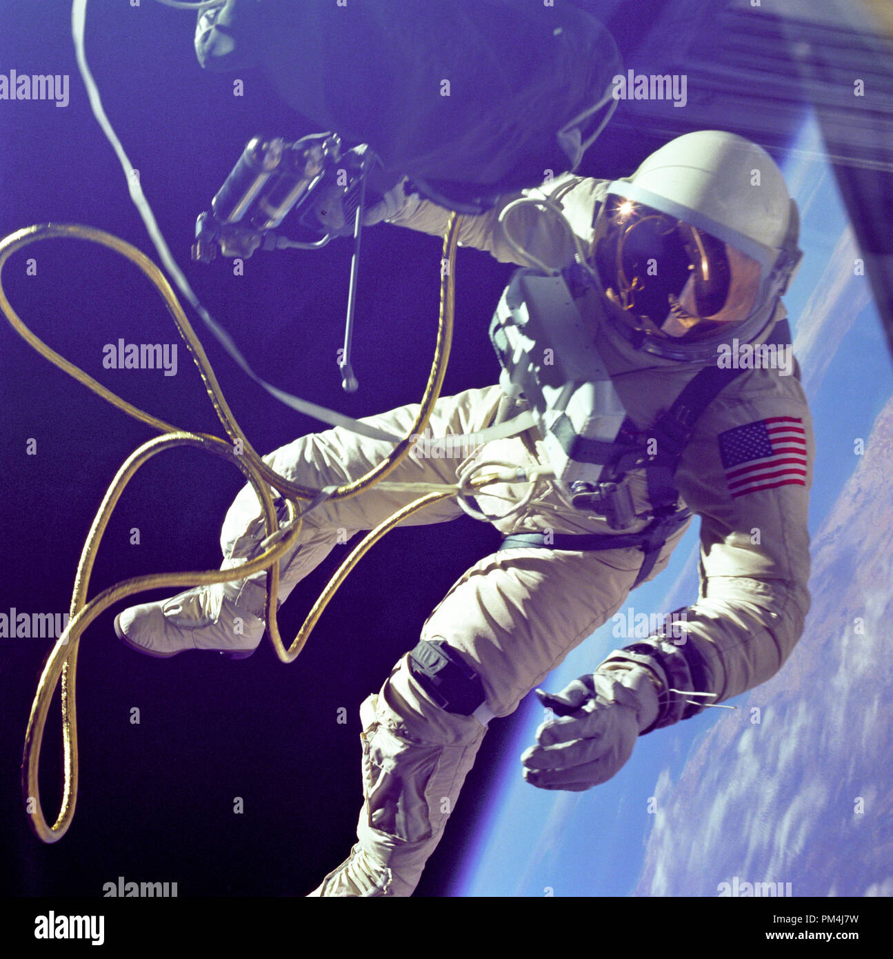 Astronaut Edward H. White, pilot for the Gemini IV spaceflight, floats in space during the first spacewalk by an American. The extravehicular activity, or spacewalk, was performed during the third Earth orbit of the Gemini IV mission. White is attached to the spacecraft by a 25-foot umbilical line and a 23-foot tether line, both wrapped in gold tape to form one cord. In his right hand White carries a Hand-Held Self-Maneuvering Unit. The visor of his helmet is gold-plated to protect him from the unfiltered rays of the sun. (June 3, 1965)   File Reference # 1003 590THA Stock Photo
