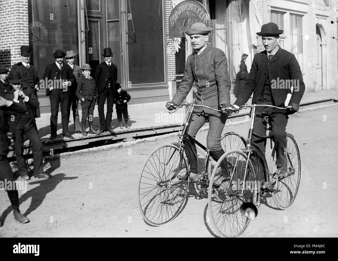 Cyclists ride their bicycles past curious onlookers in Green Bay, Wisconsin, circa 1890.   File Reference # 1003_599THA Stock Photo