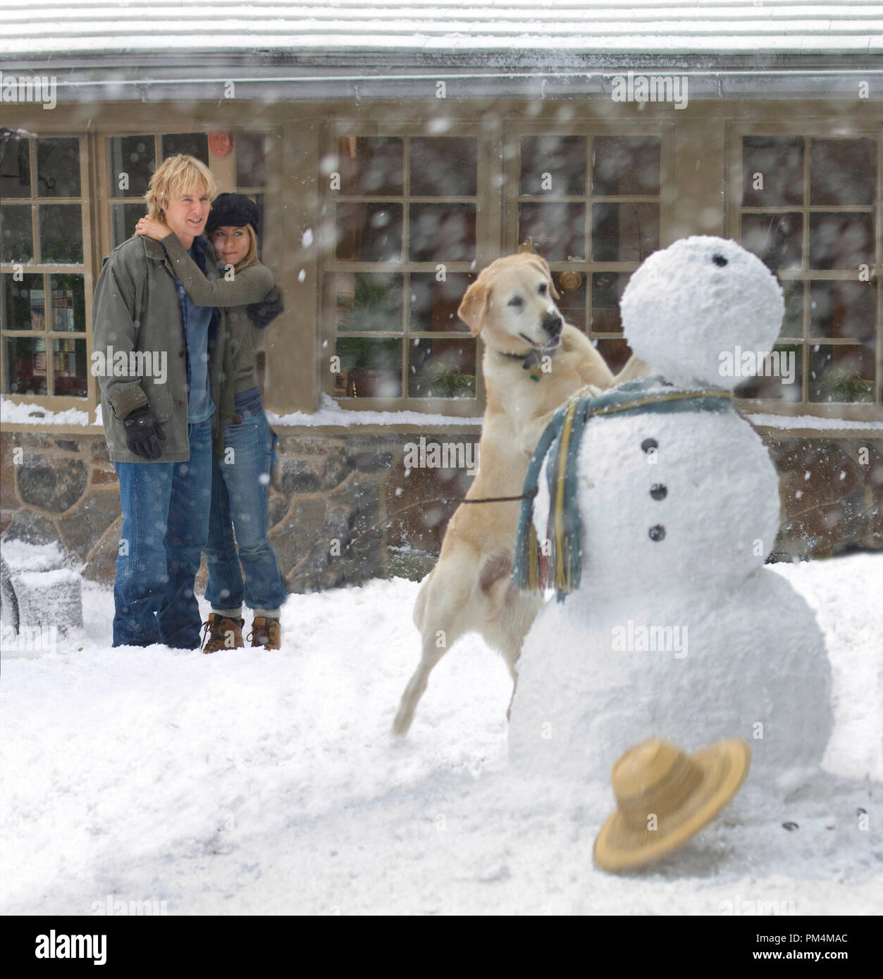 Marley makes important contributions to the building of a snowman, as John (Owen Wilson) and Jenny (Jennifer Aniston) look on. Stock Photo
