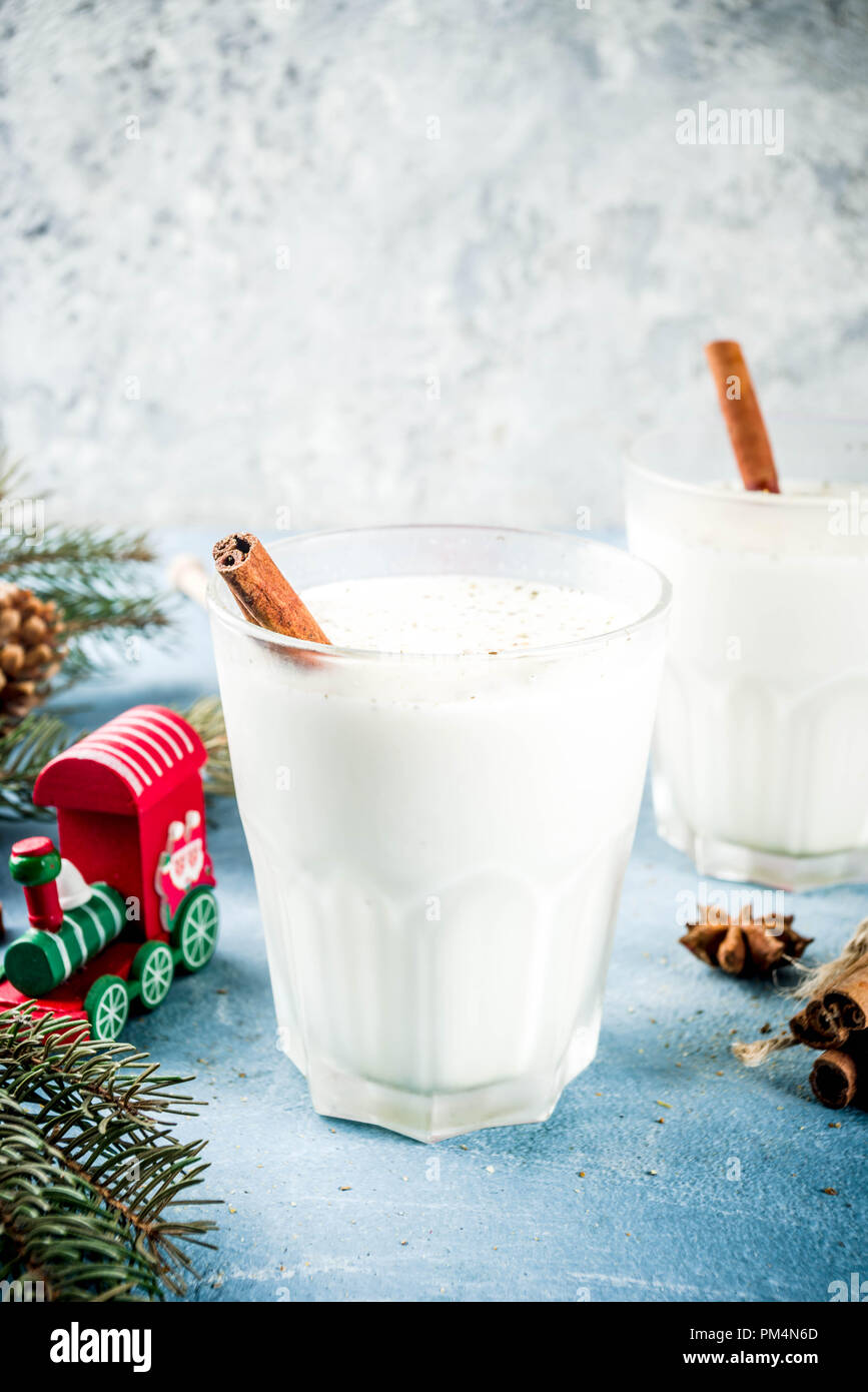 Traditional winter festive drink, sweet and spicy christmas eggnog cocktail in a glasses, on light blue background with xmas decorations, copy space t Stock Photo