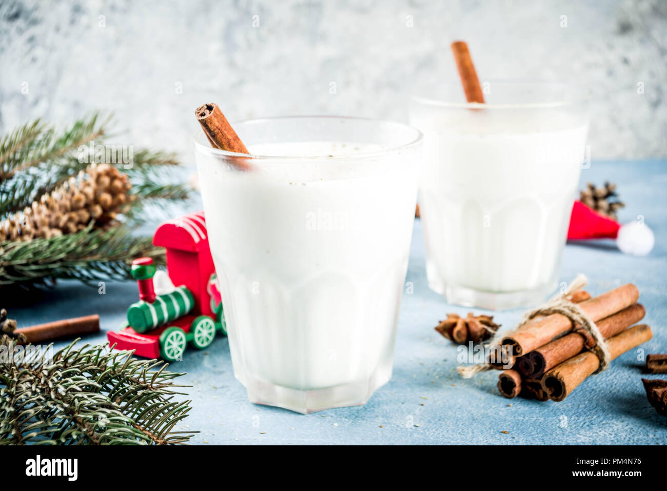 Traditional winter festive drink, sweet and spicy christmas eggnog cocktail in a glasses, on light blue background with xmas decorations, copy space t Stock Photo