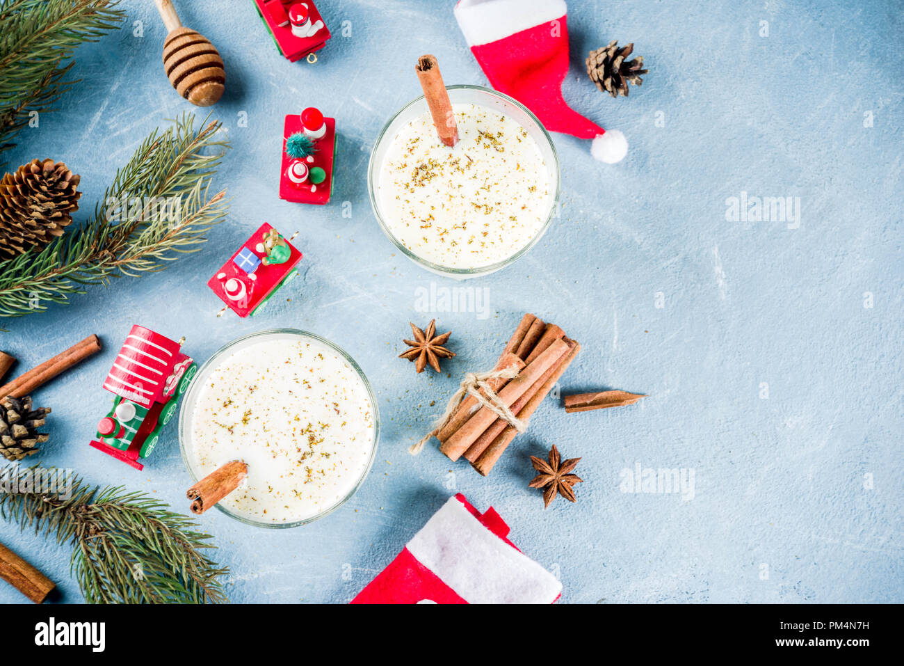 Traditional winter festive drink, sweet and spicy christmas eggnog cocktail in a glasses, on light blue background with xmas decorations, copy space t Stock Photo