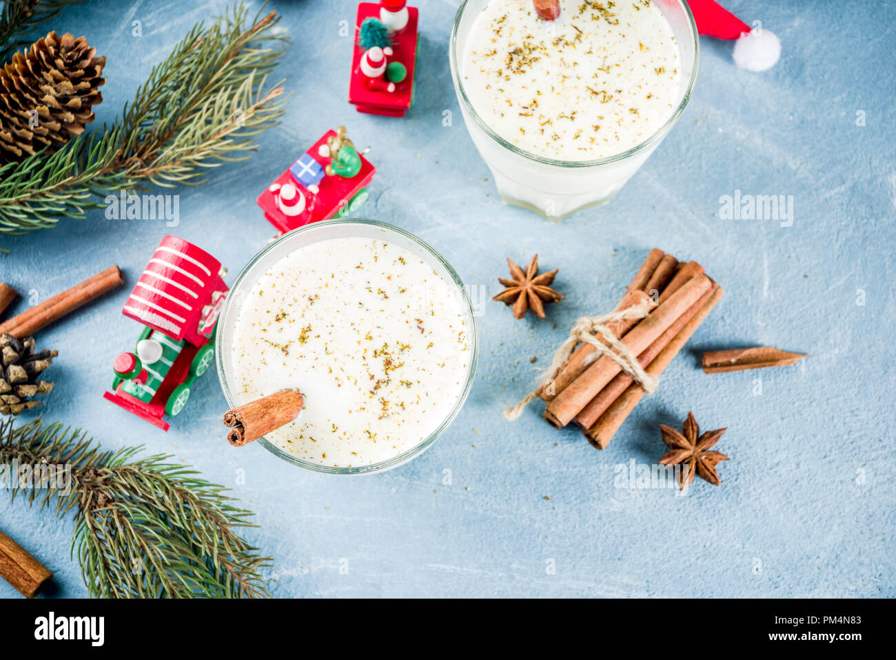 Traditional winter festive drink, sweet and spicy christmas eggnog cocktail in a glasses, on light blue background with xmas decorations, copy space t Stock Photo