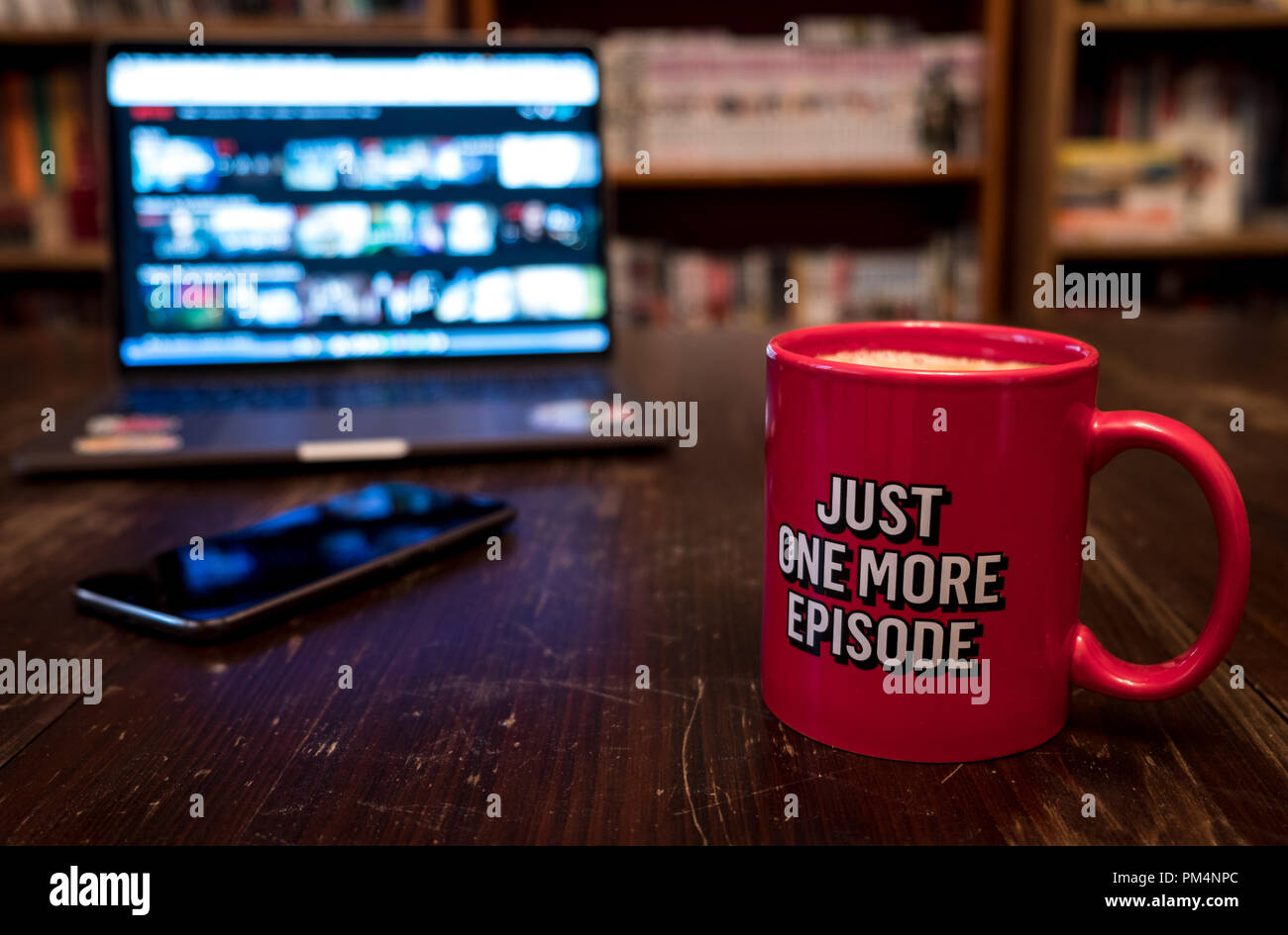 Watching series with a cup of tea on wood table with cellphone. Just one more episode. Millennial concept Stock Photo