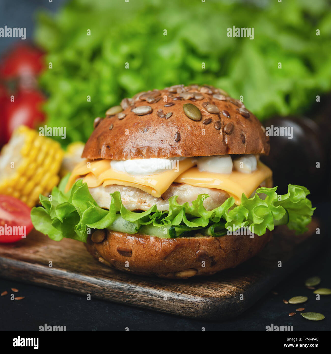 Chicken Cheeseburger with green salad and sauce. Closeup view. Tasty Cheeseburger Stock Photo