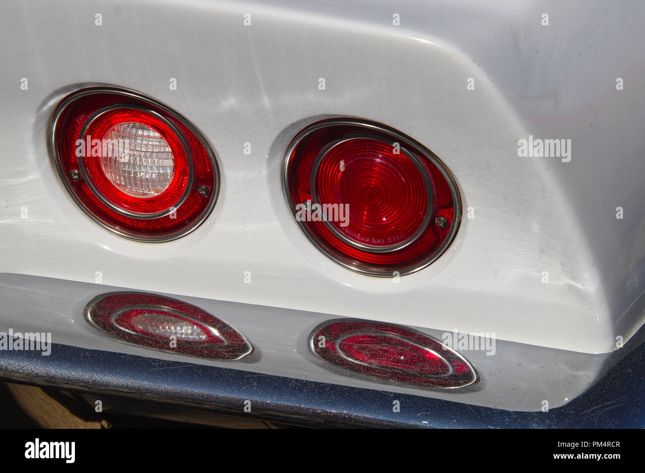 Two round tail light reflecting from chrome rear bumper of a white classic car. Stock Photo