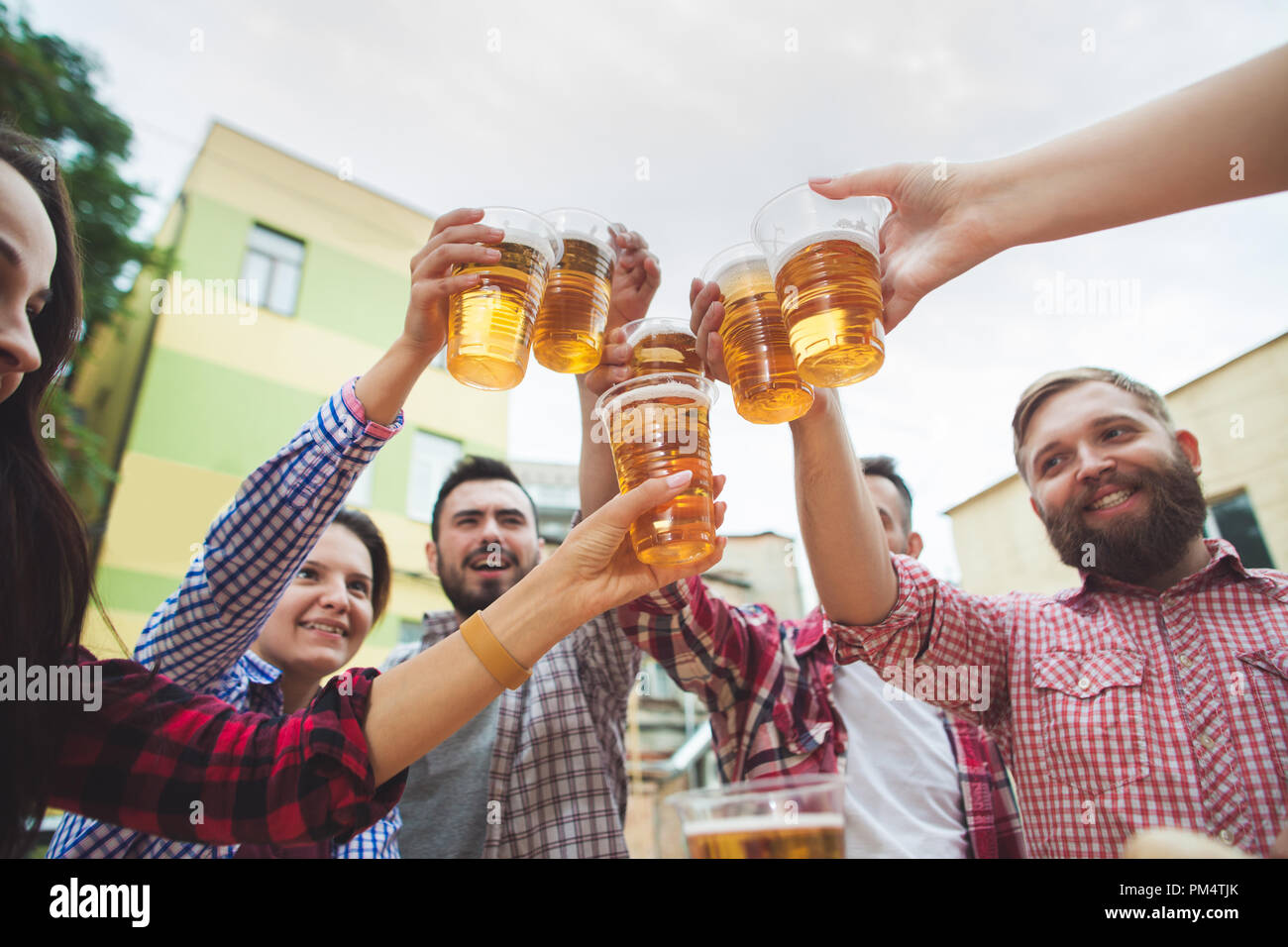 The group of friends enjoying and drinking beer at outdoor bar or pub