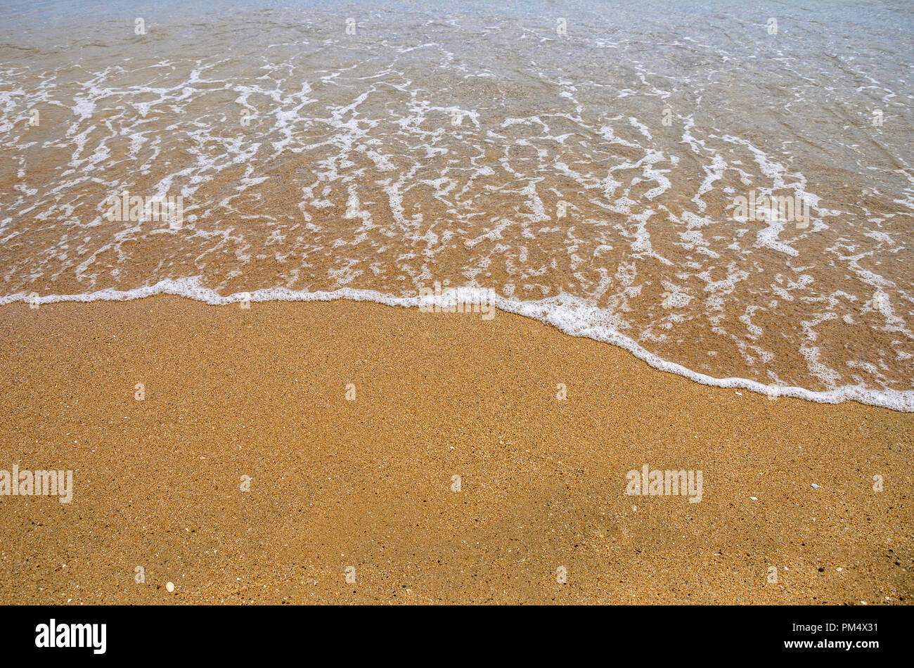 Wet sand on the beach. A part of the sea is visible. Stock Photo