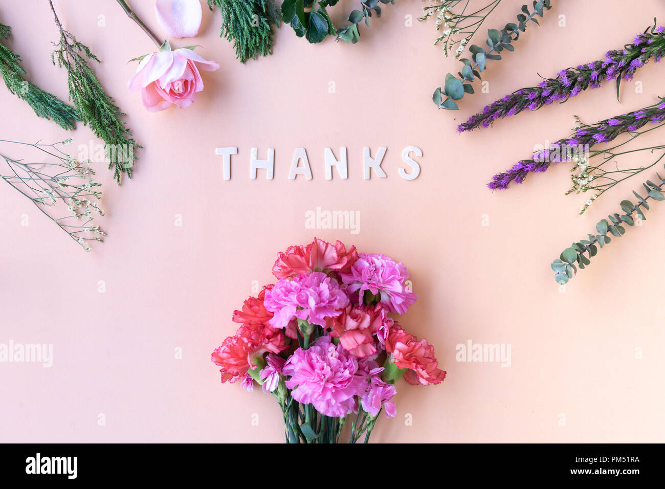 Thanks  wooden word  with fresh flowers carnations on soft cream pink background Stock Photo