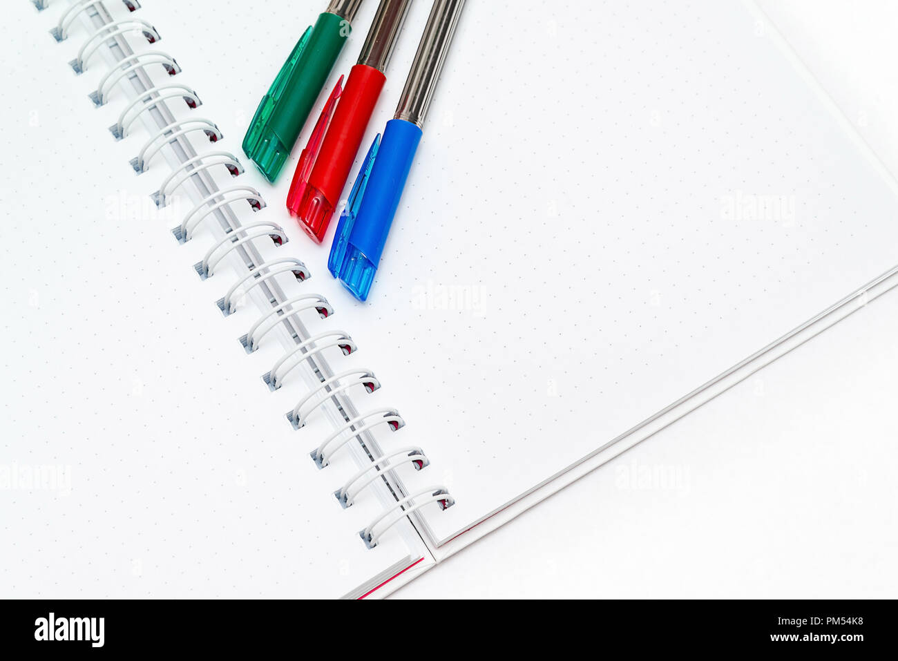 pens red, blue, green on a blank white background notebooks Stock Photo