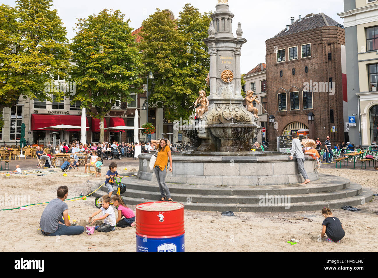 Children playing with sand and water at improvised sandbox at inner city fountain in Deventer, Netherlands Stock Photo