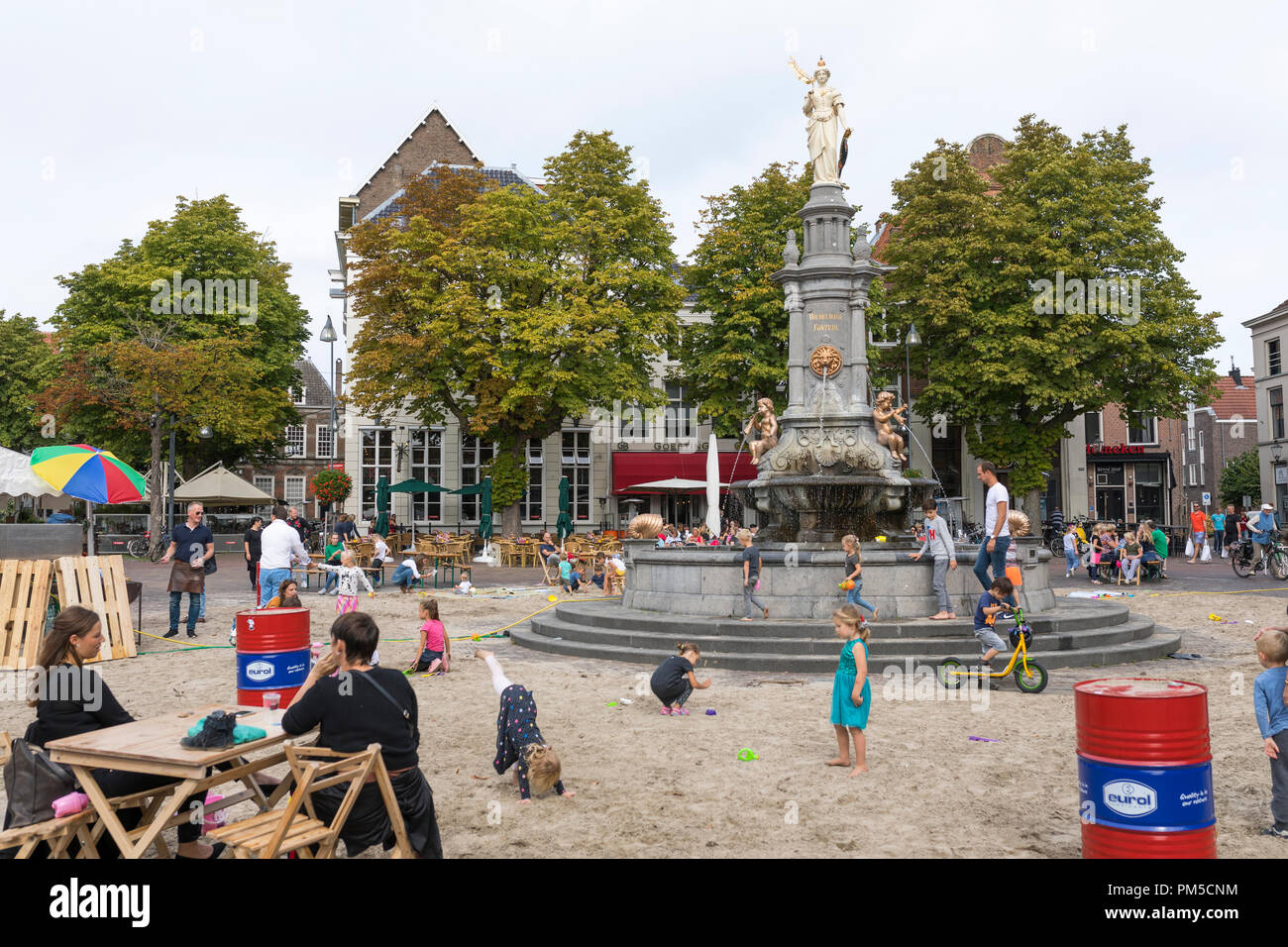 Children playing with sand and water at improvised sandbox at inner city fountain in Deventer, Netherlands Stock Photo