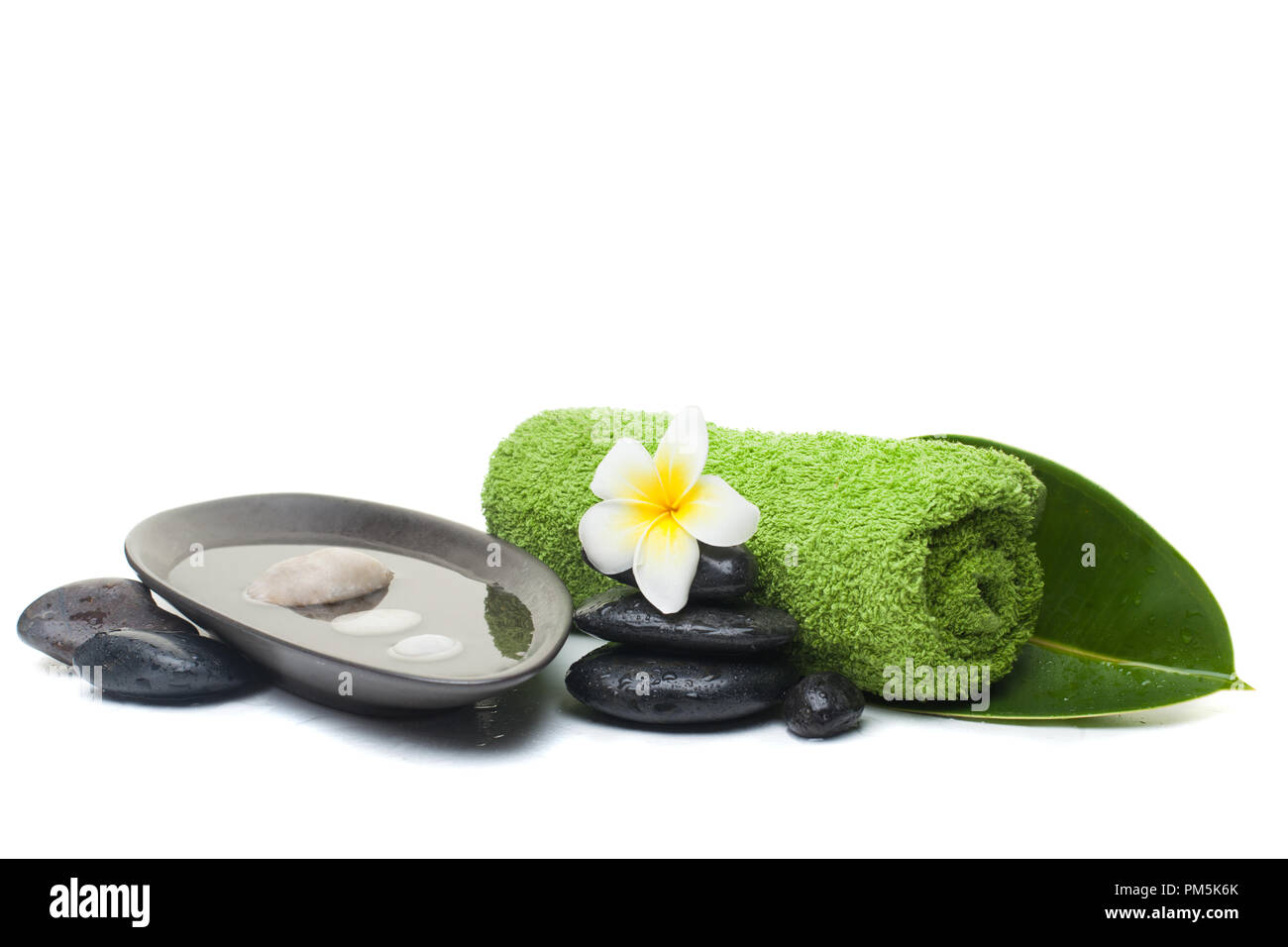 spa set with towel, black stones and tropical on white background. Stock Photo