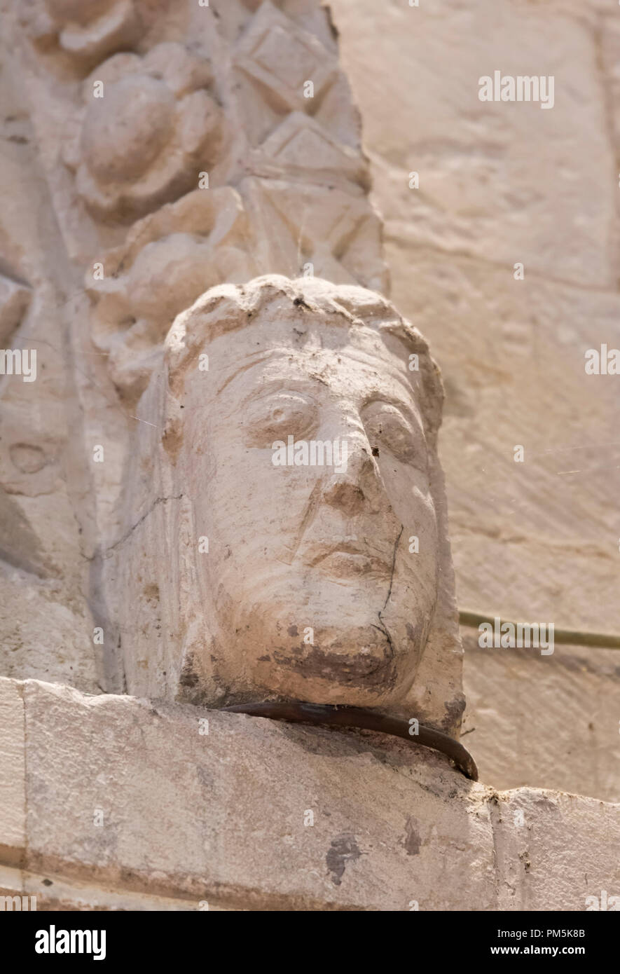 Man's head carved from a stone arch at the historic Norman St Nicolas Church in Old Shoreham, West Sussex, England, UK. Grade 1 listed building. Stock Photo