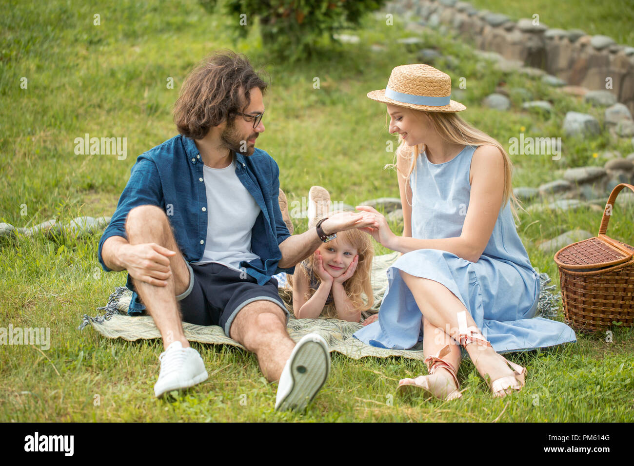 happy Family picnicking outdoors with their cute daughter, blue clothes,  woman in hat Stock Photo - Alamy