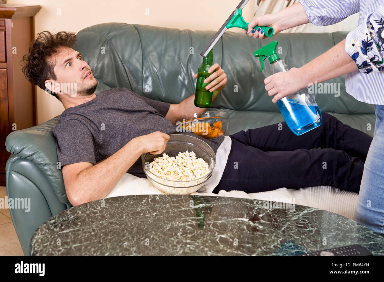 Man with beer and chips watching TV at home. Wife and husband relationship Stock Photo