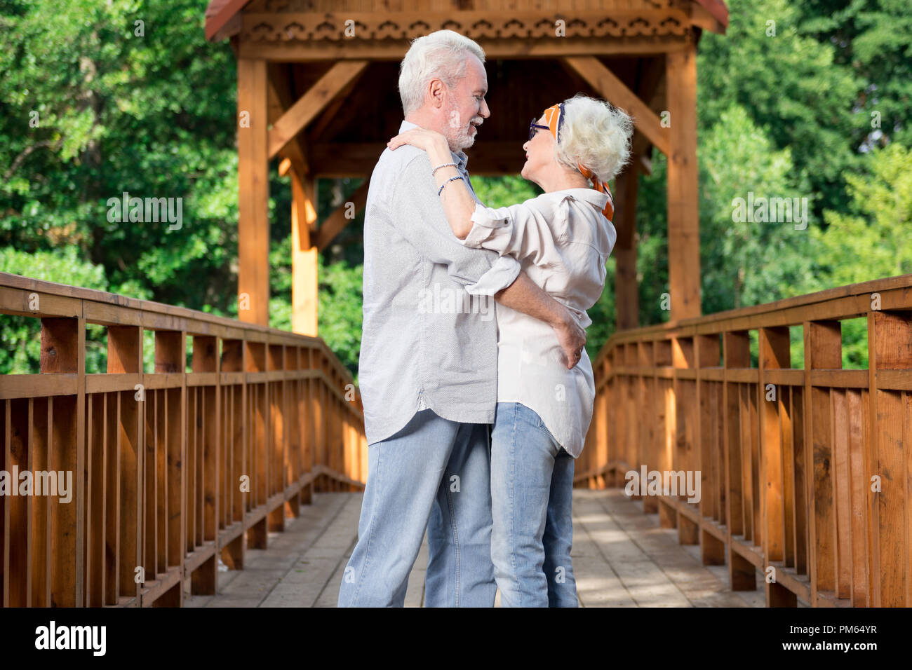 Adorable aged couple dancing while being on the bridge Stock Photo