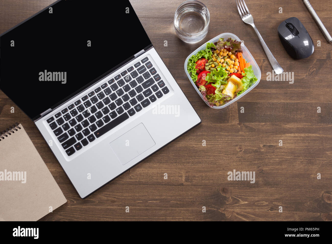 Healthy business lunch in office, salad, water on wooden table. Top