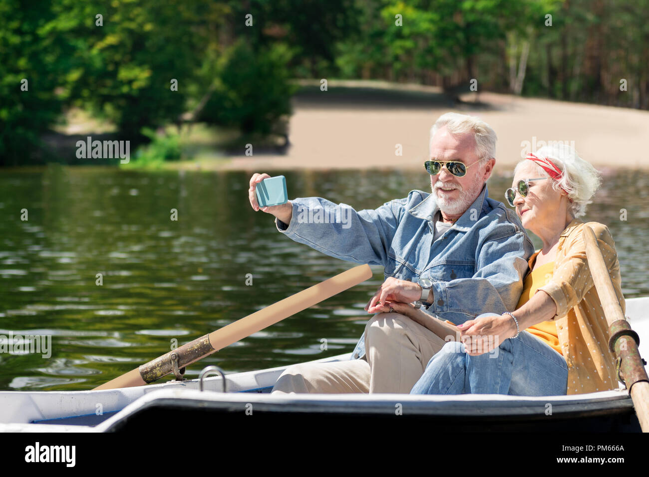 Progressive pensioners taking selfies while rowing and relaxing Stock Photo