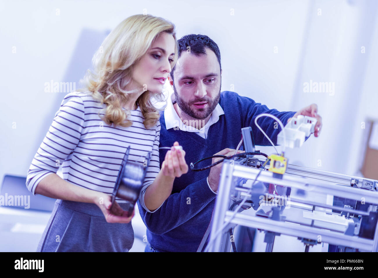 Concentrated workers checking work of 3D printer Stock Photo