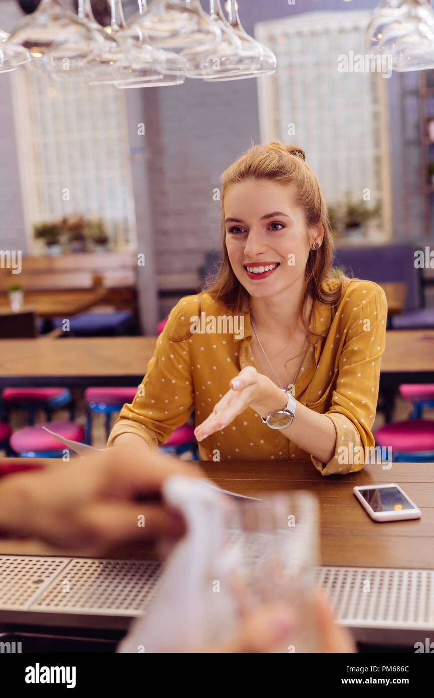 Cute young girl smiling to the barman while visiting the bar Stock Photo
