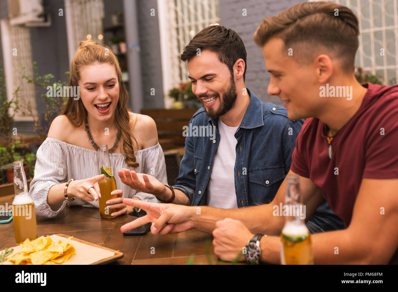 Positive friends eating snacks and playing games Stock Photo Alamy