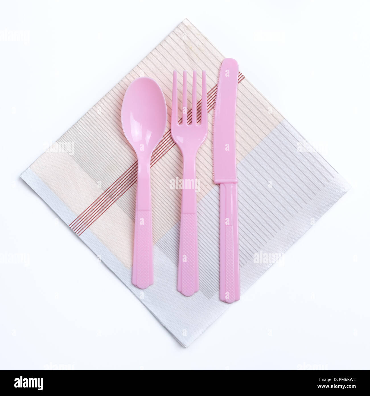 Pink color plastic fork, spoon and knife on napkin Stock Photo